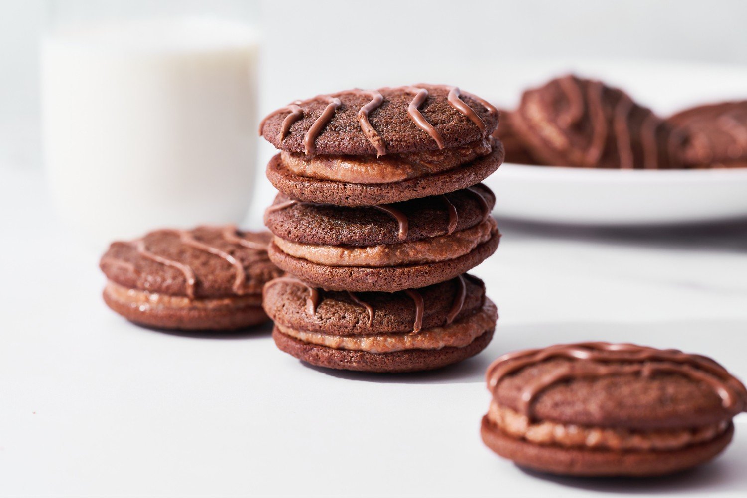 een stapel van drie fudge rounds met een glas melk erachter.