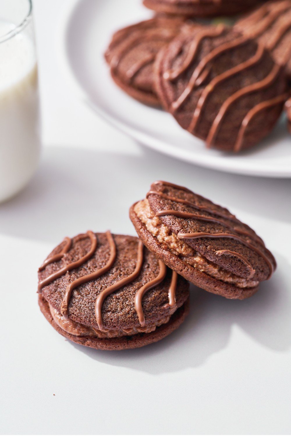 twee fudge rounds voor een schaal met meer koekjes, met een glas melk, klaar om te serveren.