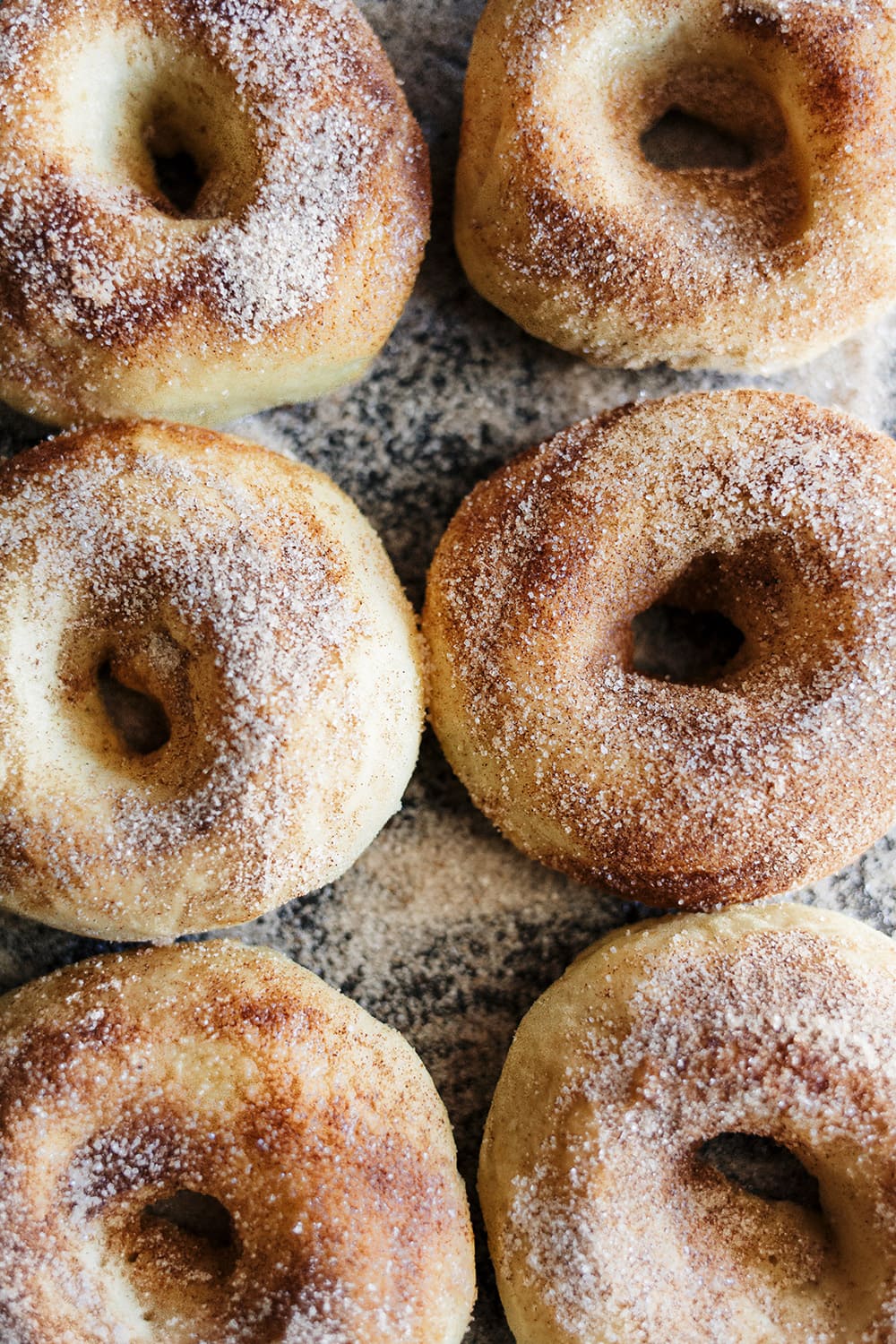 Vers gebakken appelgebak doughnuts bestrooid met kaneelsuiker, ideaal voor herfstgerechten of als dessert.