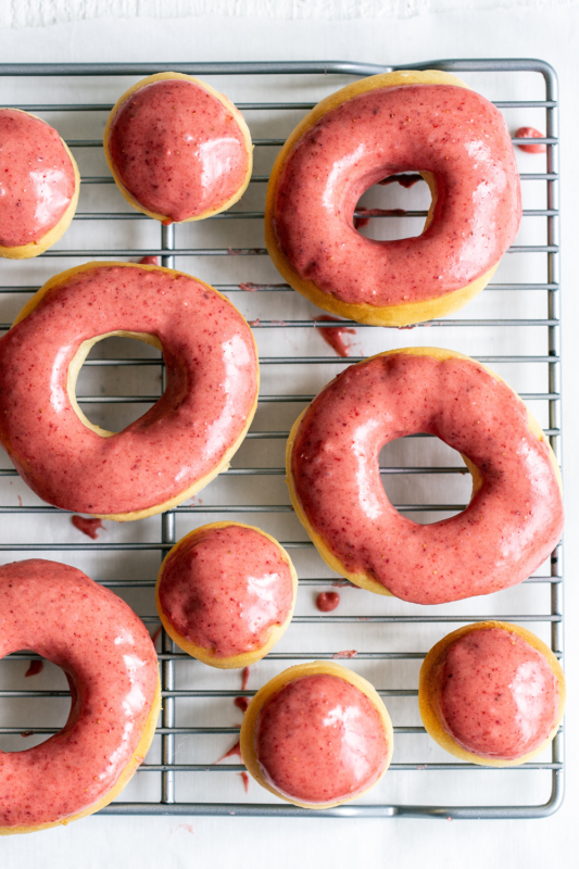 Baked strawberry lemon doughnuts drying on a wire rack, showcasing vibrant colors and perfect for dessert and bakery photography.