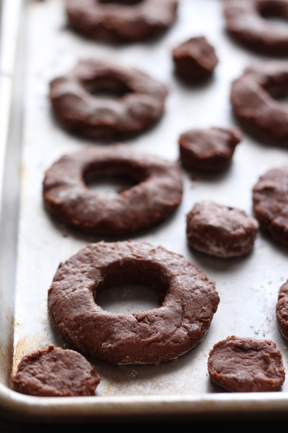 zeveral donuts and donut holes on a parchment paper-lined baking tray before being fried.