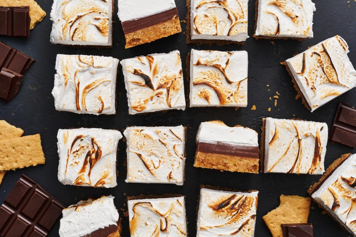 De complete pan s'mores fudge bars, perfect in plakken gesneden, met enkele bars op hun zijkant om de rijke lagen van chocolade, marshmallow en grahamcracker te tonen.