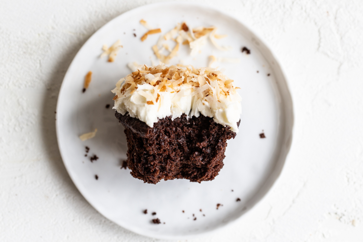 Chocolade kokos cupcake op een bord, met een hap eruit genomen, die de rijke chocoladesmaak en de romige kokosvulling laat zien.