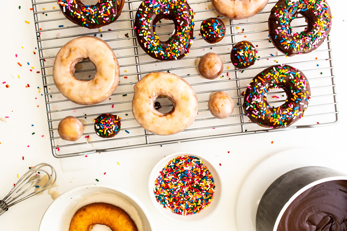 Een dozijn donuts op een draadrek terwijl het glazuur opdroogt, ideaal voor bakkerij- en food fotografie.