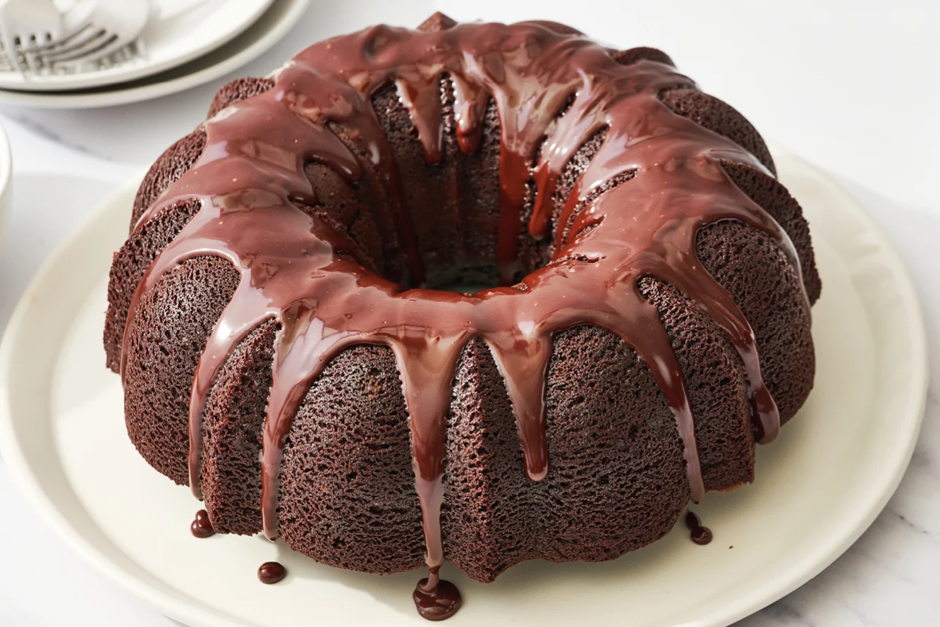 Een hele, perfect gebakken bundt cake zonder glazuur, gepresenteerd op een wit bord, klaar voor decoratie of direct serveren