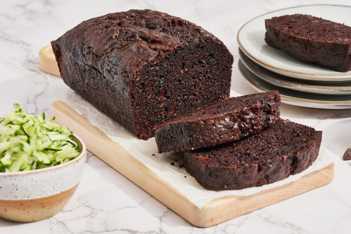 Chocolade courgettebrood wordt gesneden op een houten snijplank, met perfect zachte en rijke plakken.