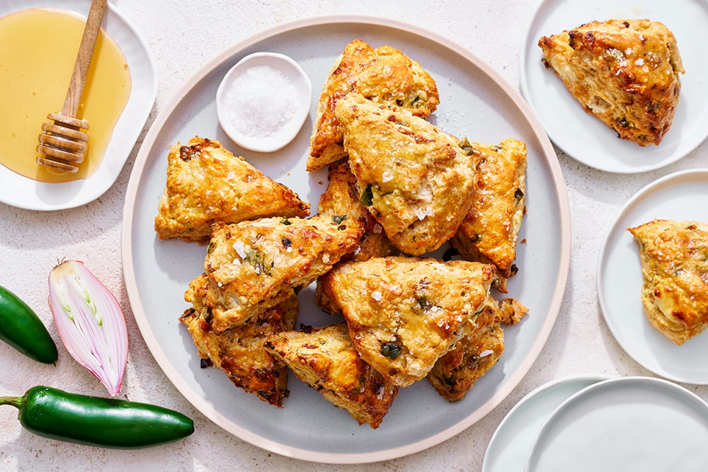 A plate of savory shallot, jalapeño, goat cheese, and honey scones, perfect for breakfast or savory snack photography