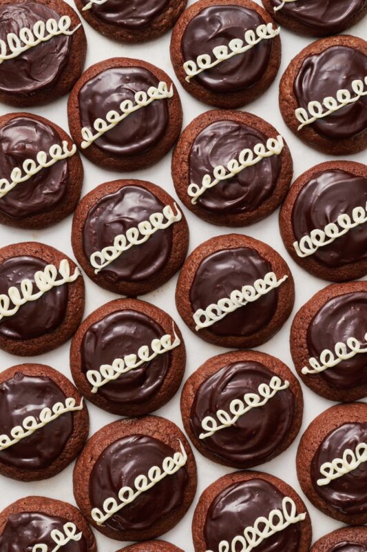 Chocolade koekjes getopt met ganache en sierlijke lussen van witte glazuur die het hele frame vullen