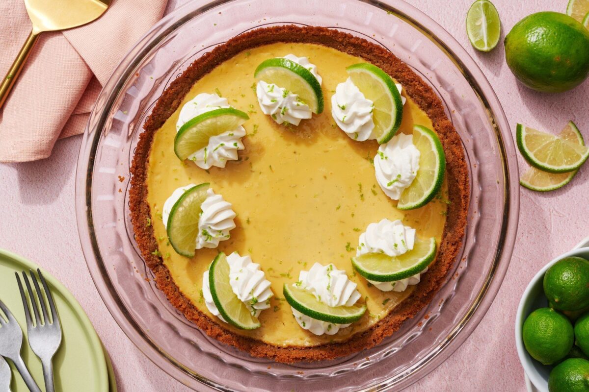 Een hele gebakken key lime pie, gegarneerd met luchtige slagroom en verse limoenplakjes, perfect voor dessert- en bakkerijfotografie