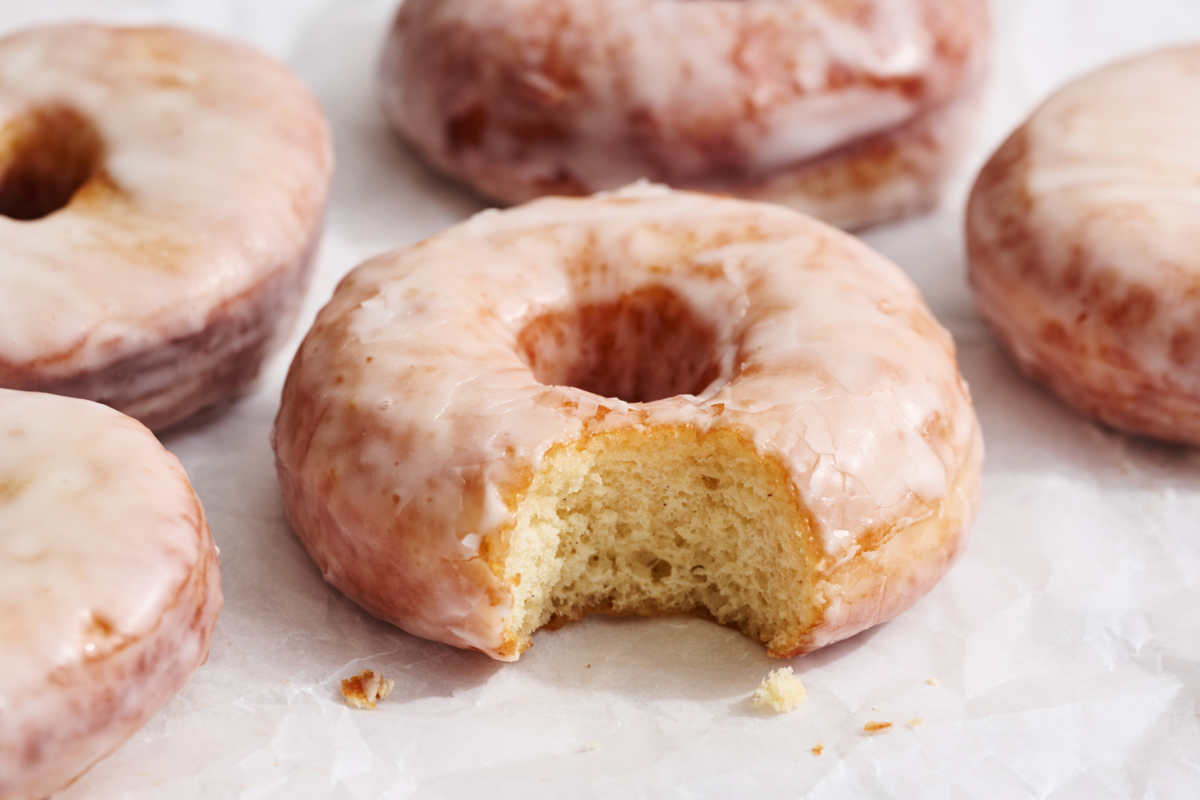 Geglazuurde donut met een hap eruit, revealing de zachte binnenkant en het glanzende glazuur.