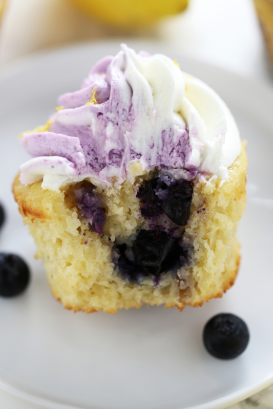 A cupcake bitten in half, revealing juicy blueberries inside, perfect for showcasing dessert and bakery photography.