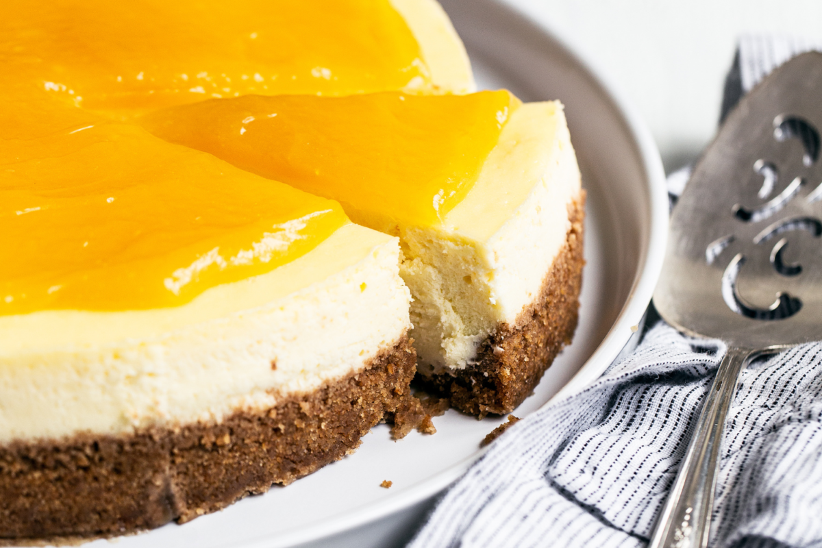 Hele cheesecake bedekt met romige citroencurd op een bord, perfect voor dessert- en bakkerijfotografie.