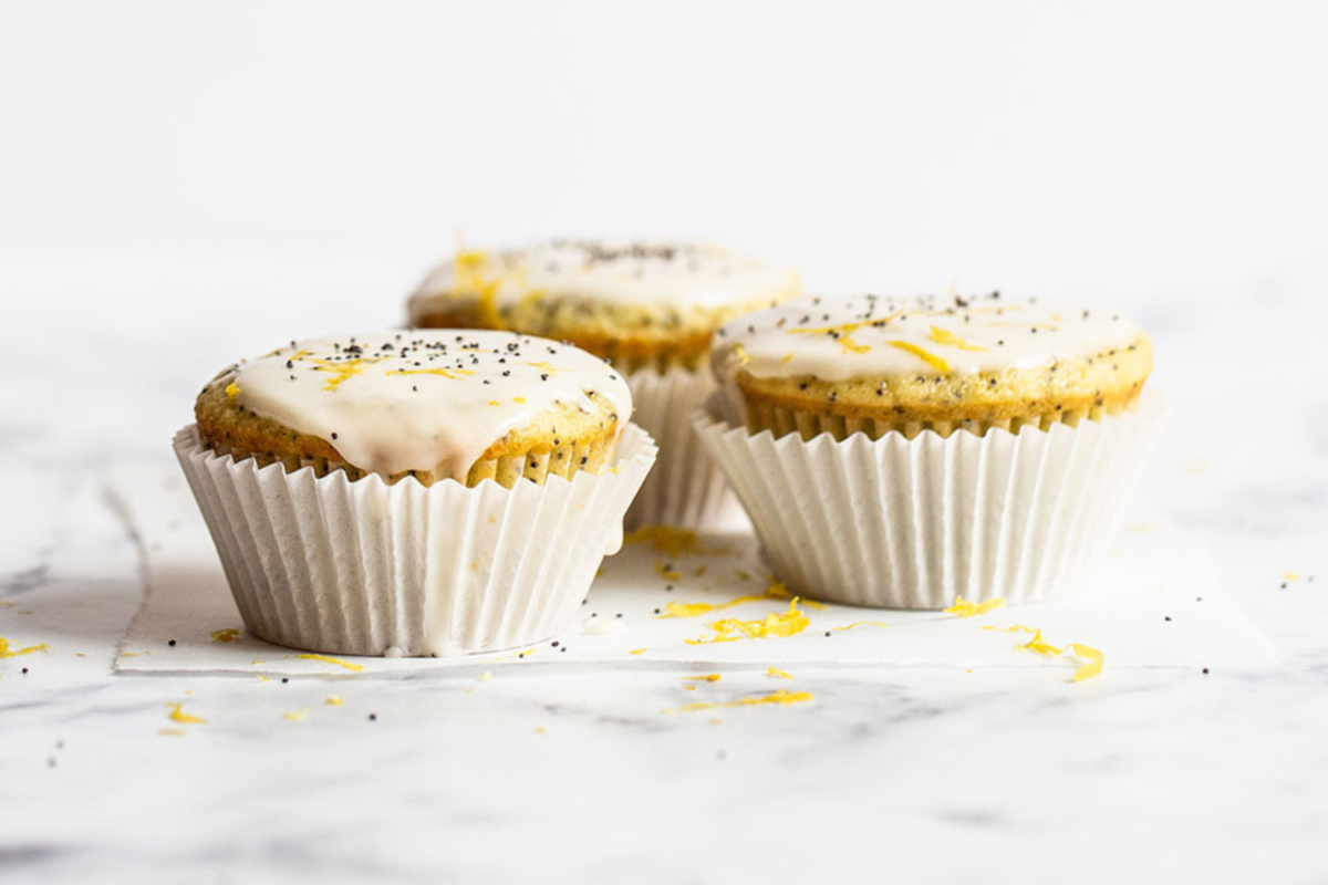 Drie geglazuurde citroen-maanzaadmuffins, perfect gebakken met een frisse citroenglazuur.