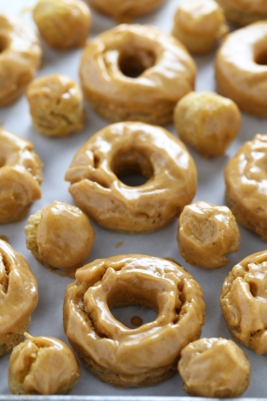 Glazed pumpkin old fashioned doughnuts and donut holes on a tray, ready to serve as a fall treat.Glazuur pumpkin old fashioned donuts en donut holes op een dienblad, klaar om te serveren als herfsttraktatie