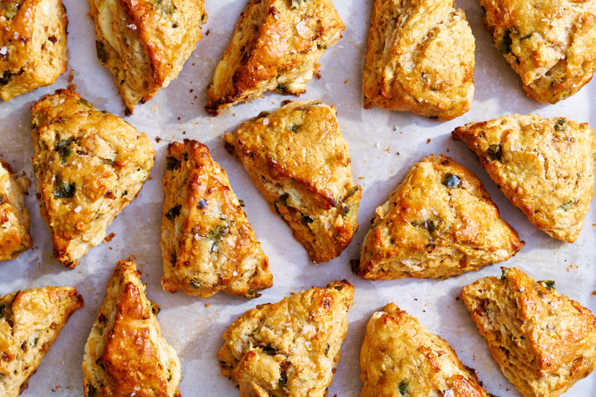 Overhead shot of multiple shallot, jalapeño, goat cheese, and honey scones on a baking sheet, ready to be baked, ideal for recipe and baking photography.