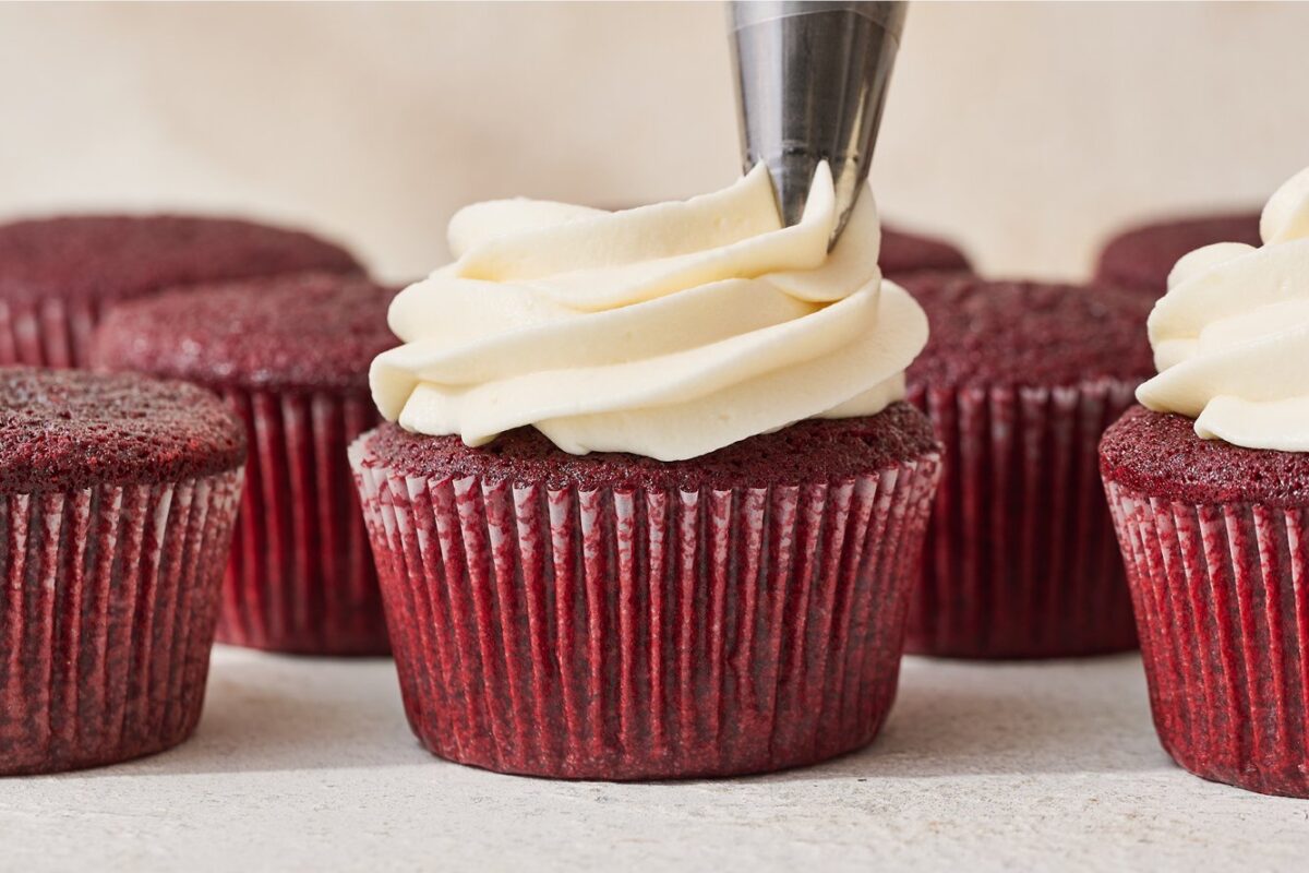 Het aanbrengen van romige cream cheese frosting op een luchtige red velvet cupcake.