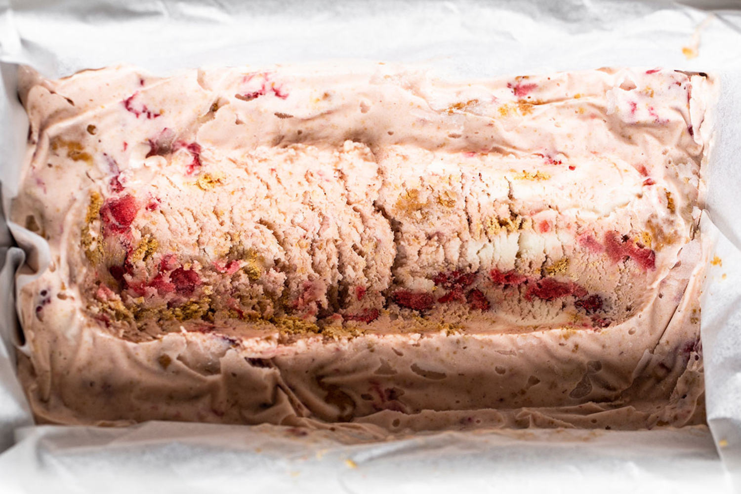 Close-up van romig aardbeien cheesecake ijs met een rijke laag aardbeien en een smeuïge kaasachtige smaak.