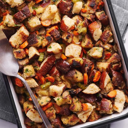 Close-up van een lepel vol pretzel stuffing, net uit de pan gehaald, klaar om te serveren.