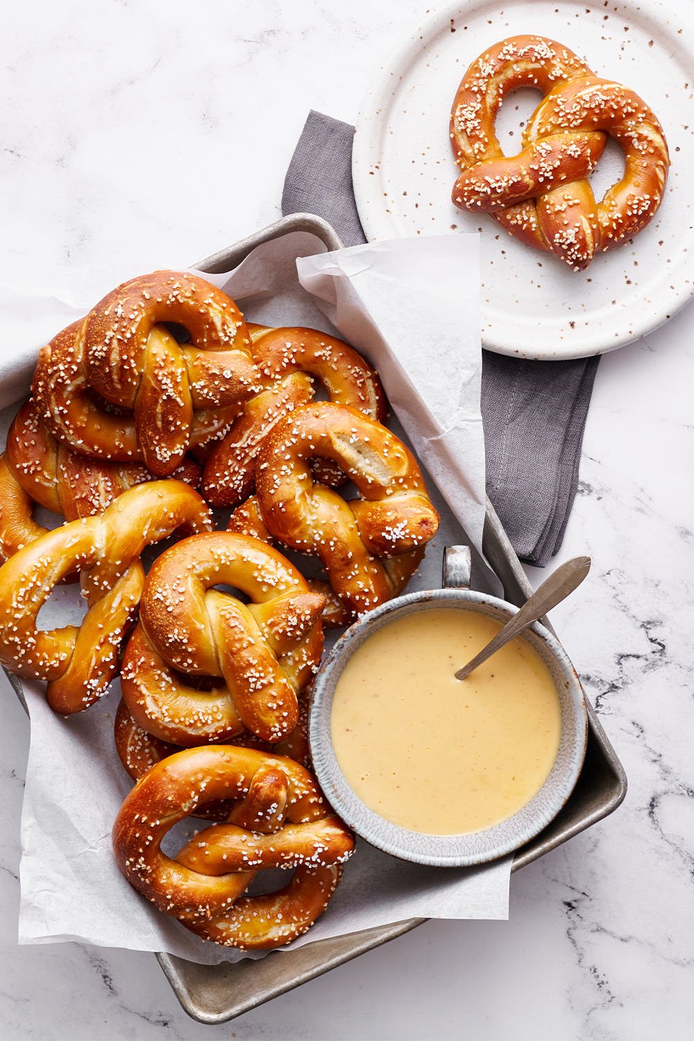 Een grote schaal huisgemaakte pretzels met een kom bierkaasdip, klaar om te serveren.