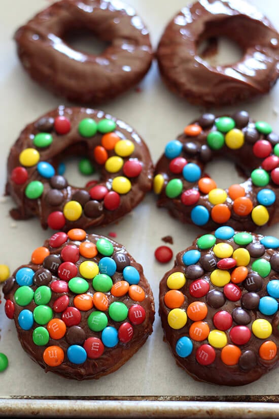 M&M Cake Doughnuts zijn gefrituurde perfectie, bedekt met een dikke chocoladeglazuur en knapperige m&m's en zijn veel sneller te maken dan gistdonuts!